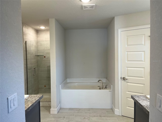 bathroom featuring shower with separate bathtub, vanity, and a textured ceiling