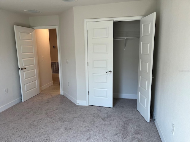 unfurnished bedroom featuring a closet and light colored carpet