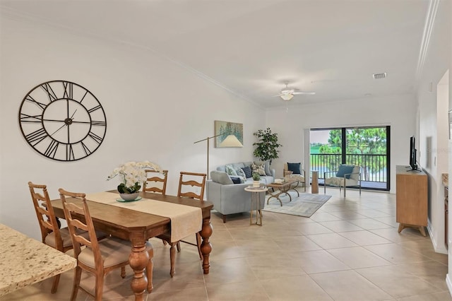 tiled dining area featuring ceiling fan, vaulted ceiling, and ornamental molding