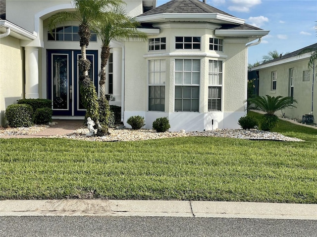 view of exterior entry with a yard and stucco siding