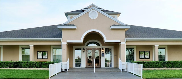255 Royal Palm Dr, Davenport, FL 33837 - view of exterior entry with a shingled roof, french doors, a lawn, and stucco siding