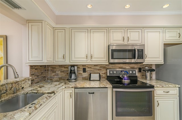 kitchen with cream cabinets, tasteful backsplash, appliances with stainless steel finishes, and light stone counters