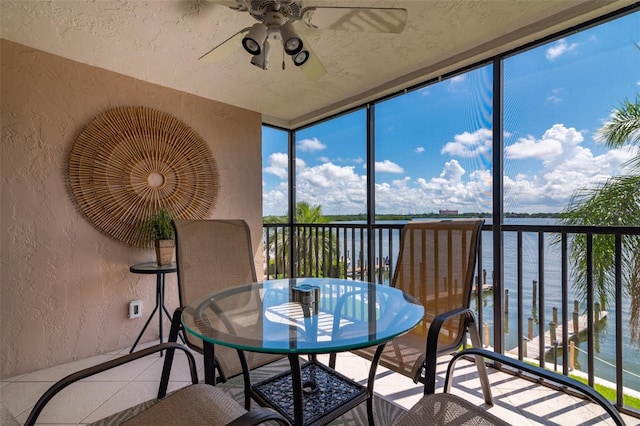 sunroom featuring ceiling fan and a water view