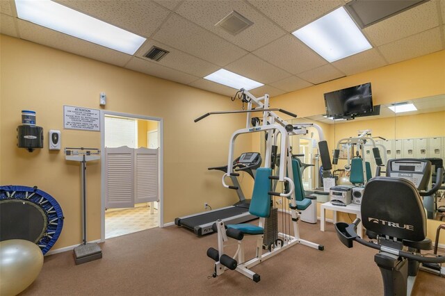 gym with a paneled ceiling and tile floors