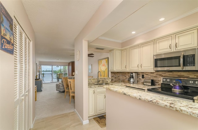 kitchen with light stone countertops, black range with electric stovetop, light carpet, backsplash, and sink