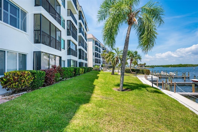 dock area with a yard, a balcony, and a water view