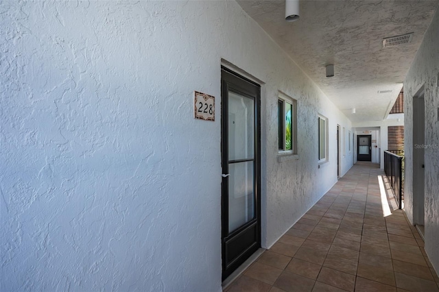 hall with dark tile flooring