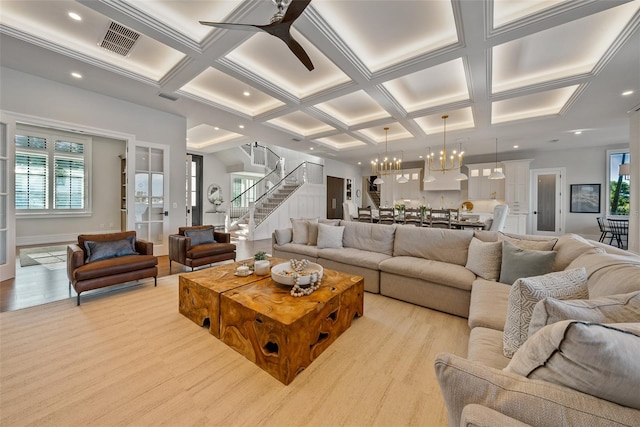 living room with ceiling fan with notable chandelier, light hardwood / wood-style floors, beam ceiling, and coffered ceiling