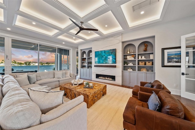 living room featuring light wood-type flooring, coffered ceiling, built in features, beamed ceiling, and a fireplace