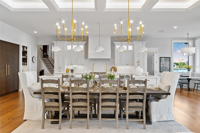 dining room featuring light wood-type flooring, ornamental molding, and an inviting chandelier