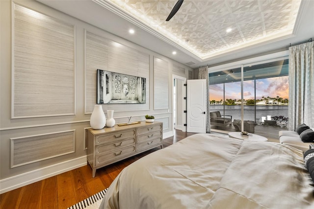 bedroom featuring access to outside, a raised ceiling, crown molding, dark hardwood / wood-style floors, and ceiling fan