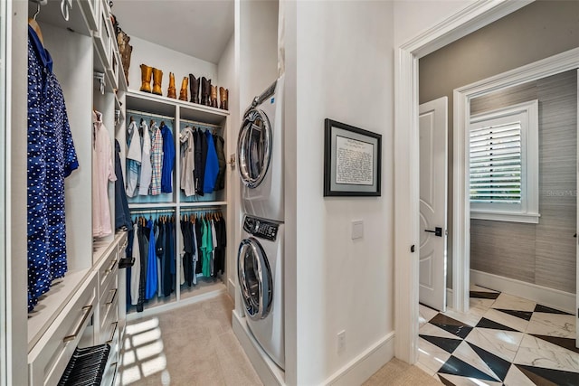 clothes washing area featuring stacked washer / dryer and light carpet