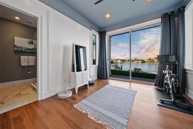 exercise area with a water view and light hardwood / wood-style floors