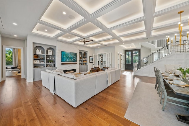 living room with ceiling fan with notable chandelier, light hardwood / wood-style floors, and plenty of natural light