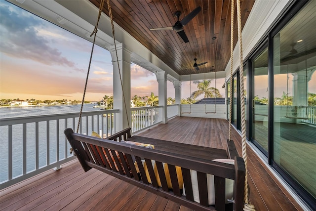 deck at dusk featuring ceiling fan and a water view