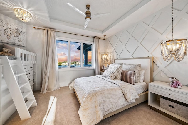 carpeted bedroom with ceiling fan with notable chandelier and a raised ceiling