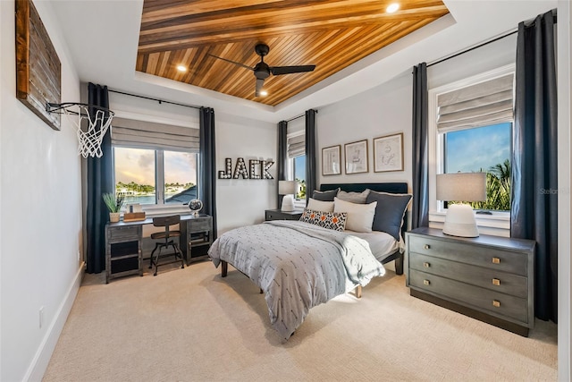 carpeted bedroom with a tray ceiling, ceiling fan, and wood ceiling