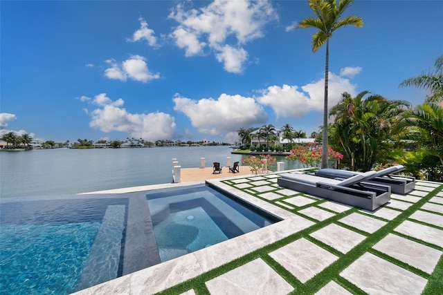 view of swimming pool with a patio area, a water view, and an in ground hot tub