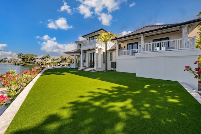 back of house with a balcony, central AC, a lawn, and a water view