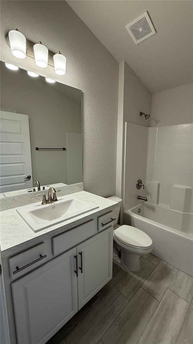 full bathroom with hardwood / wood-style floors, vaulted ceiling,  shower combination, toilet, and vanity