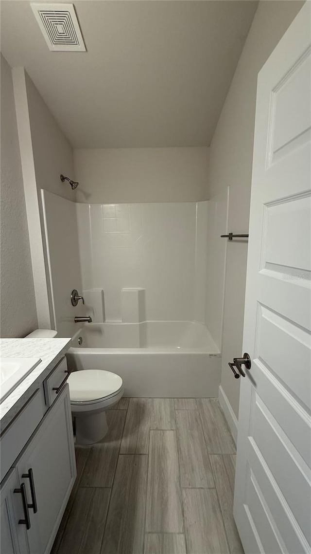 full bathroom with hardwood / wood-style flooring, vanity, shower / bathtub combination, and toilet