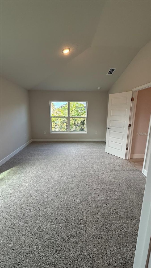 carpeted empty room with lofted ceiling