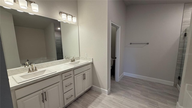 bathroom with a bath, vanity, wood-type flooring, and toilet