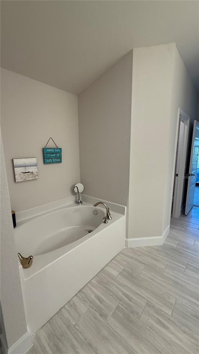 full bath featuring a garden tub and baseboards