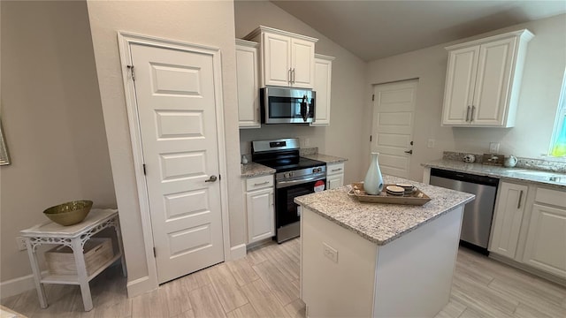 kitchen with lofted ceiling, white cabinetry, a kitchen island, and appliances with stainless steel finishes