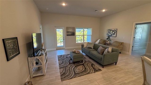 living room featuring light wood-type flooring, visible vents, baseboards, and recessed lighting