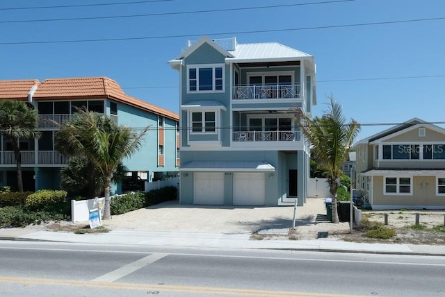 raised beach house featuring stucco siding, an attached garage, driveway, and a balcony
