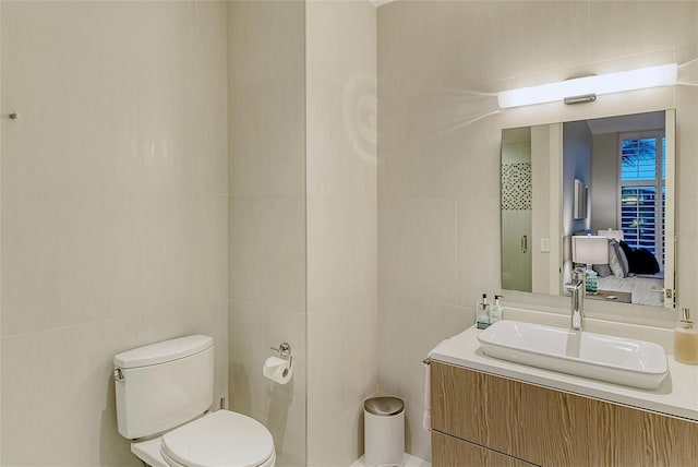 bathroom featuring tile walls, toilet, and vanity