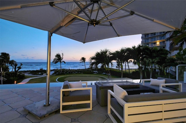 patio terrace at dusk featuring a water view and outdoor lounge area