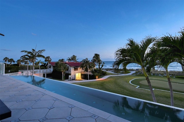 view of swimming pool with a lawn and a water view