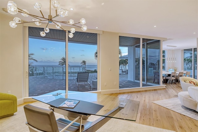 dining space with an inviting chandelier, a healthy amount of sunlight, a water view, and wood-type flooring