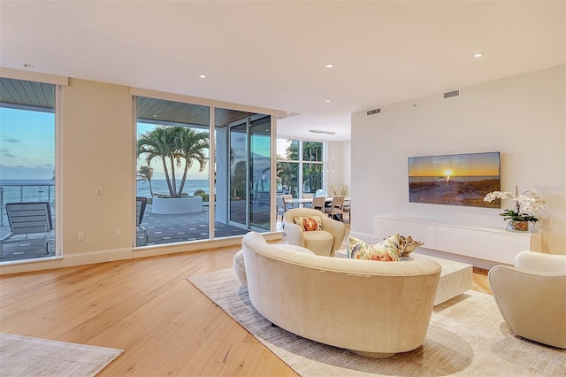 living room featuring light wood-type flooring and floor to ceiling windows