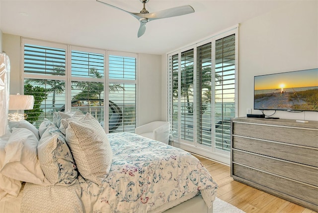 bedroom with ceiling fan, a wall of windows, and light hardwood / wood-style flooring