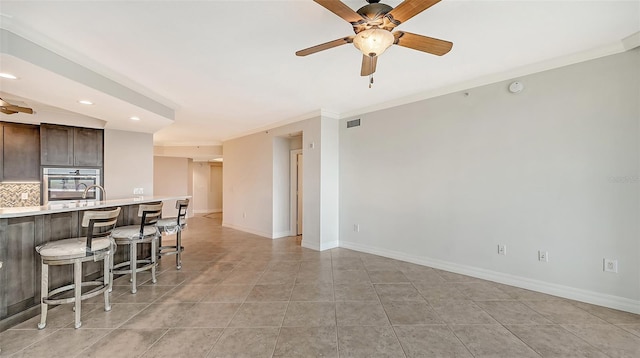 living room featuring light tile flooring, ceiling fan, sink, and crown molding