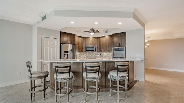 kitchen with ceiling fan with notable chandelier, a breakfast bar, stainless steel appliances, light tile floors, and tasteful backsplash