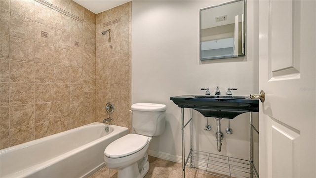 bathroom with tile floors, toilet, and tiled shower / bath