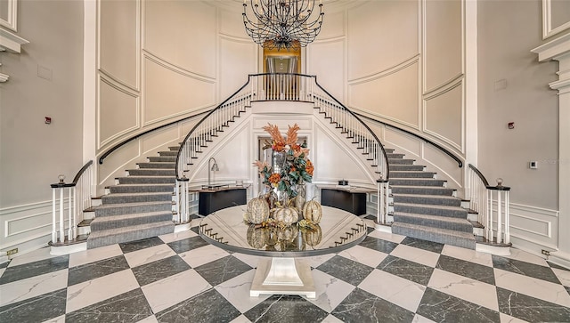 staircase featuring a high ceiling, a chandelier, crown molding, and light tile floors