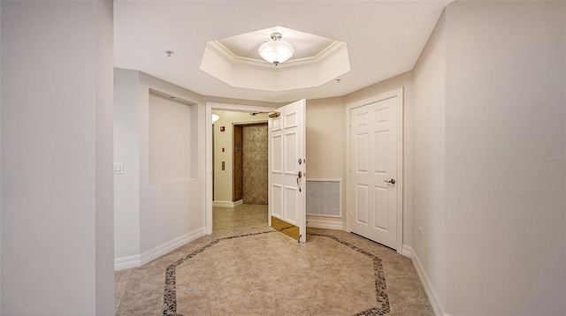 hallway with a tray ceiling and light tile floors