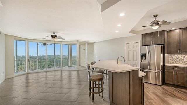 kitchen with stainless steel fridge with ice dispenser, a breakfast bar area, backsplash, and ceiling fan