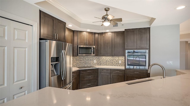 kitchen with stainless steel appliances, light stone countertops, ceiling fan, backsplash, and sink