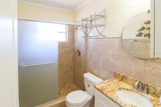 bathroom with toilet, vanity, tile walls, ornamental molding, and a tile shower