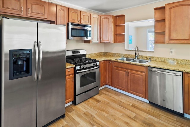 kitchen with stainless steel appliances, light stone countertops, crown molding, light hardwood / wood-style flooring, and sink