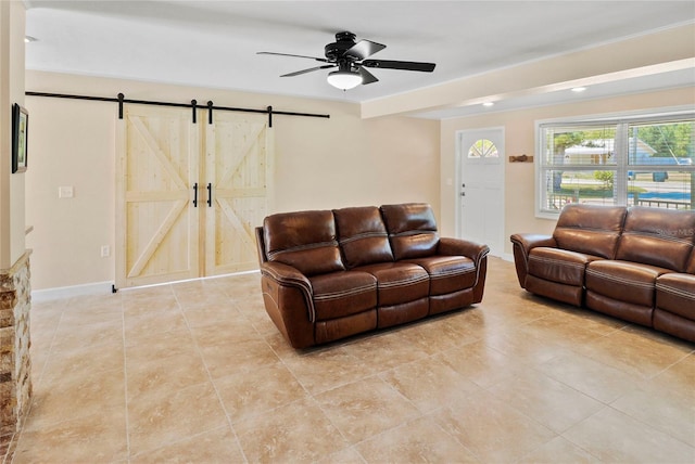 living room with ceiling fan and a barn door