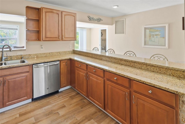 kitchen with light stone countertops, sink, plenty of natural light, light wood-type flooring, and stainless steel dishwasher