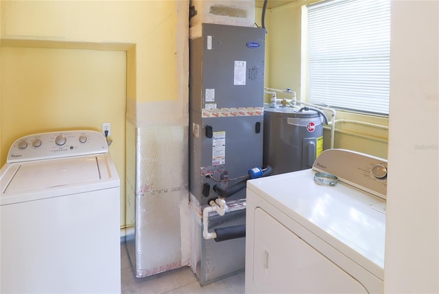 laundry area featuring electric water heater, a healthy amount of sunlight, washer and dryer, and light tile patterned floors