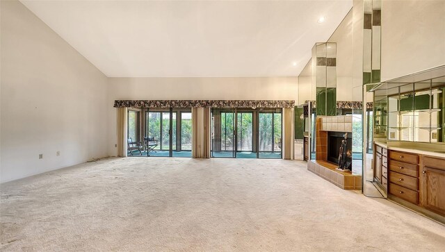 unfurnished living room with light carpet, high vaulted ceiling, and a fireplace